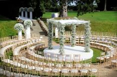 an outdoor ceremony set up with white flowers and greenery on the aisle, surrounded by chairs