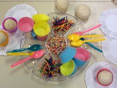 there are many plastic cups and spoons on the table with lace doily around them