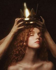 a woman with a crown on top of her head and hands over her head,