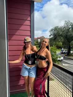 two women standing next to each other in front of a purple building and green grass