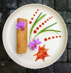 a white plate topped with food and flowers on top of a brick floored area