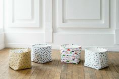 three small baskets sitting on top of a hard wood floor next to a white wall