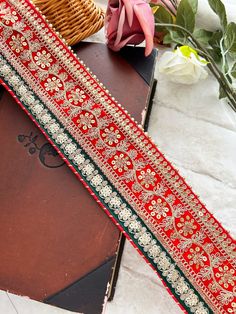 a close up of a red and green ribbon on a table next to some flowers