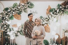 a man and woman standing in front of a floral backdrop