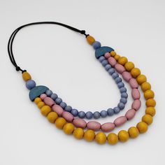 "Discover the beauty of Sylca Designs' handcrafted Wood Bead Cailee statement necklace! This artistic piece features a stunning triple strand design, carefully strung with captivating wood beads in hues of orange, blue, and wine. Each necklace is uniquely handcrafted, making it a wearable work of art. Whether you're dressing up for a special occasion or adding a pop of color to your everyday look, this comfortable and lightweight design on an adjustable cord is sure to be your go-to accessory. A Blue Multi-strand Wooden Bead Necklaces, Handmade Orange Multi-strand Necklace, Handmade Multicolor Multi-strand Layered Necklace, Multicolor Handmade Multi-strand Layered Necklace, Adjustable Orange Multi-strand Necklaces, Necklace Orange, Colorful Necklace, Necklace Colorful, Bold Necklace