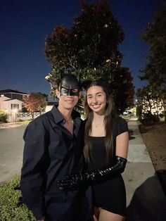 two people dressed up as batman and catwoman pose for a photo in front of a house