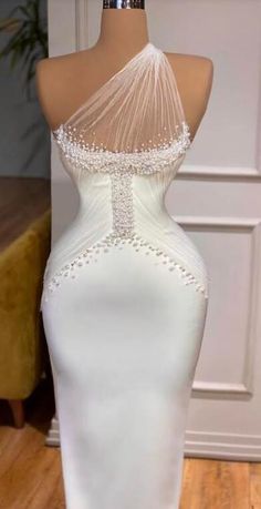 a white wedding dress with beading on the shoulders and neckline is displayed in front of a mannequin