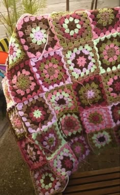 a crocheted blanket sitting on top of a wooden bench