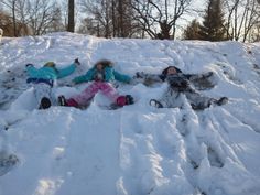 three children are laying in the snow together