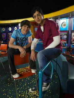 two young men sitting on chairs in front of a tv screen with confetti all over them