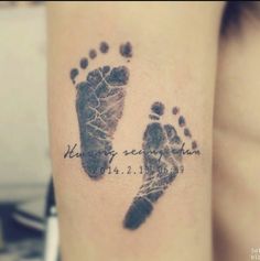 a small tattoo with two footprints and the words, he is my son in heaven