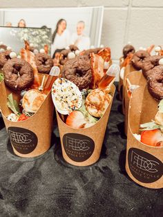 three brown paper cups filled with food on top of a table