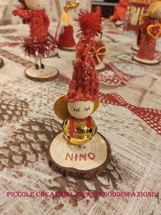 a table topped with figurines and ornaments on top of a wooden slice covered in red thread