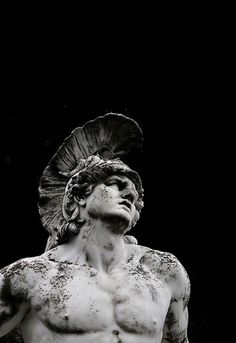 black and white photograph of a man with no shirt on standing in front of a dark background