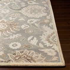 an area rug with flowers and leaves on the side, in light blue and beige colors