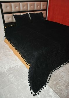 a black bedspread with pom - poms on the bottom and sides