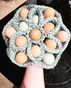 a hand is holding a crocheted dishcloth with eggs in it