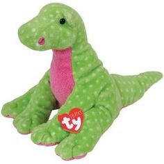 a green and pink dinosaur stuffed animal with a heart on it's chest, laying down