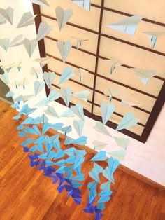 some blue and white paper birds hanging from the ceiling