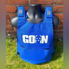 a blue vest with the word gon on it sitting in front of a brick wall