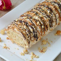 a close up of a pastry on a plate with nuts and chocolate drizzle