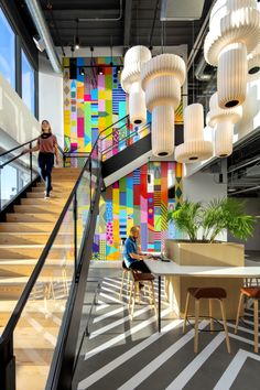 two people walking up and down the stairs in an office with colorful wallpaper on the walls