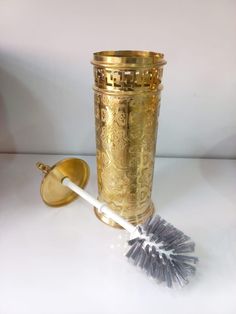 a metal cup with a brush next to it