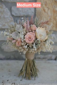 a bouquet of flowers sitting on top of a wooden table next to a stone wall