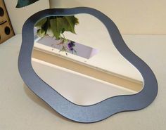 a mirror sitting on top of a table next to a vase with flowers in it