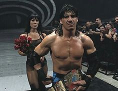 the wrestler is holding his belt and posing for a photo with two women behind him