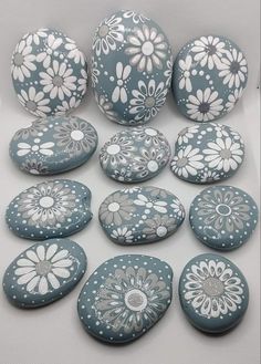 several blue and white painted rocks with flowers on them