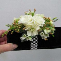 a bouquet of white flowers and greenery is being held by someone's hand