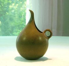 a brown vase sitting on top of a white table next to a green planter