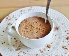 a cup of hot chocolate with a spoon in it on a saucer and plate