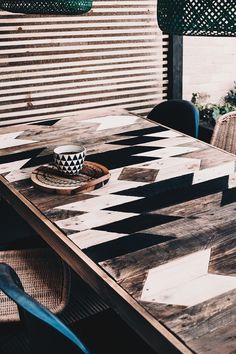 a wooden table with a black and white checkered pattern on it, next to wicker chairs