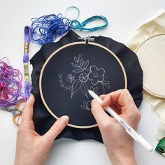 a person is drawing on a black piece of fabric with white crayons and markers