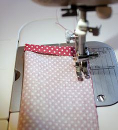 the sewing machine is working on the pink polka dot fabric with white dots and red ribbon