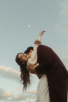 a man and woman standing next to each other under a blue sky with white clouds