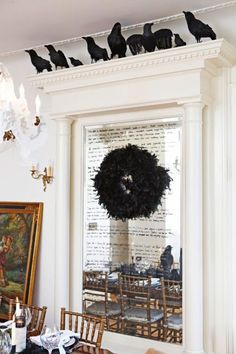 a flock of birds sitting on top of a chandelier above a dining room table