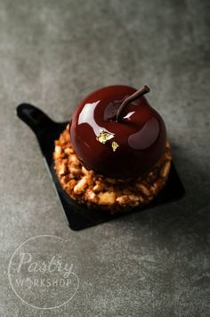 an apple on top of some kind of pastry that is sitting on a black plate