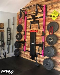 a home gym with wooden walls and various exercise equipment on the wall, as well as an overhead pull up bar