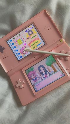 a pink nintendo wii game system sitting on top of a white sheet with a toothbrush in it's mouth