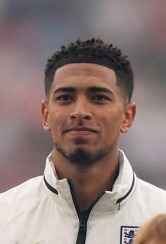 a close up of a soccer player wearing a white jacket and black tie with his head turned to the side