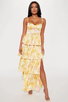 a woman wearing a yellow floral print dress with spaghetti straps and thigh high slits