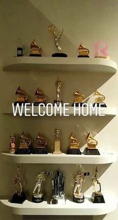 there are many trophies on the shelves in front of this sign that says welcome home