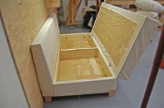 an open wooden box sitting on top of a floor next to some wood planks