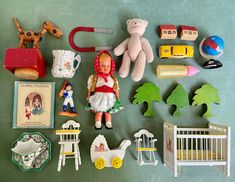 there are many toys on the table and one doll is laying next to it's crib