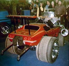 an orange race car sitting on top of a blue floor next to other cars and people