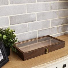 a wooden box sitting on top of a counter next to a potted green plant