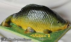 a large fish statue sitting on top of a grass covered field next to a white sheet